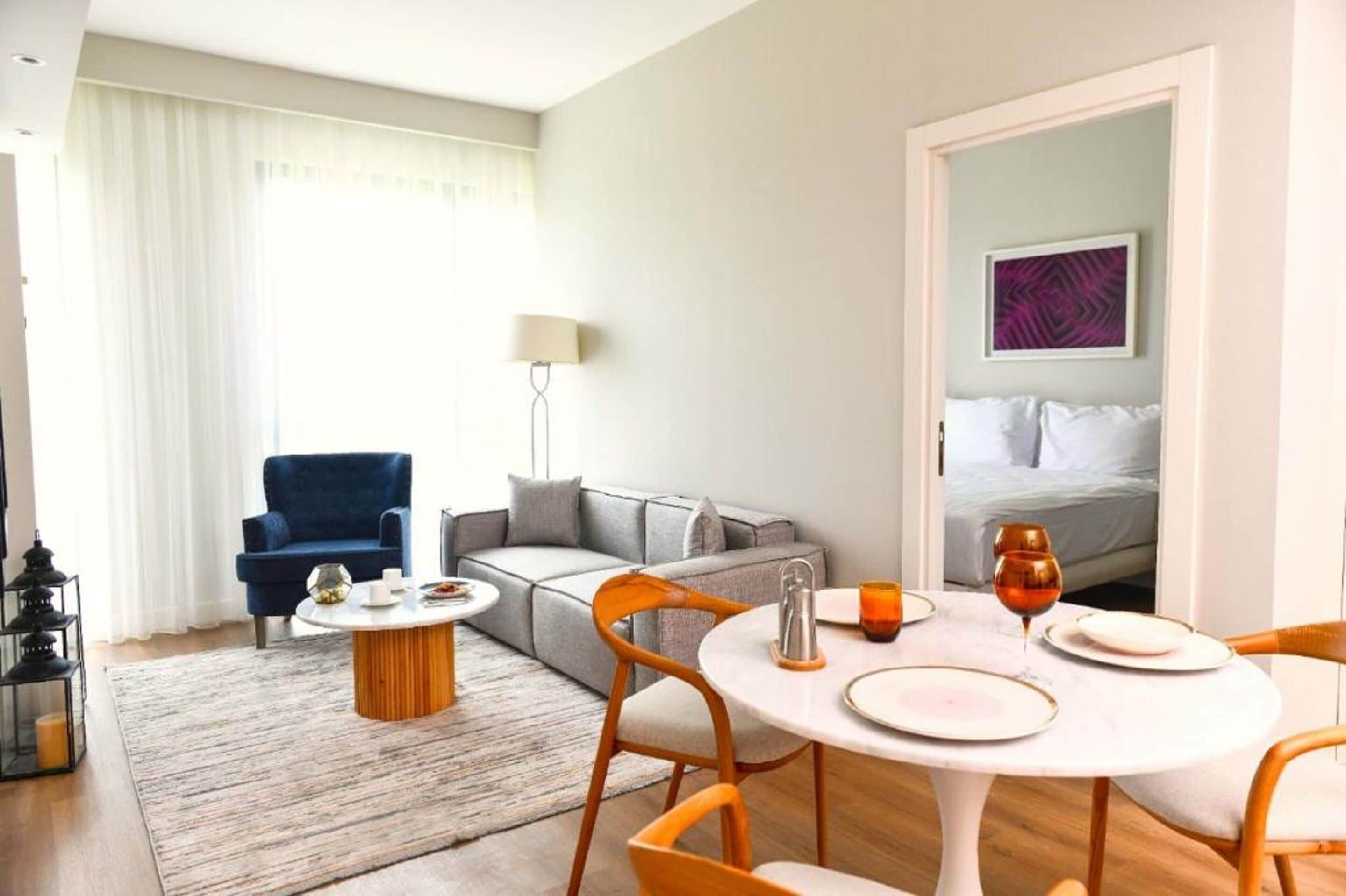 Una habitación de hotel moderna con comedor, sofá, lámpara y cama.