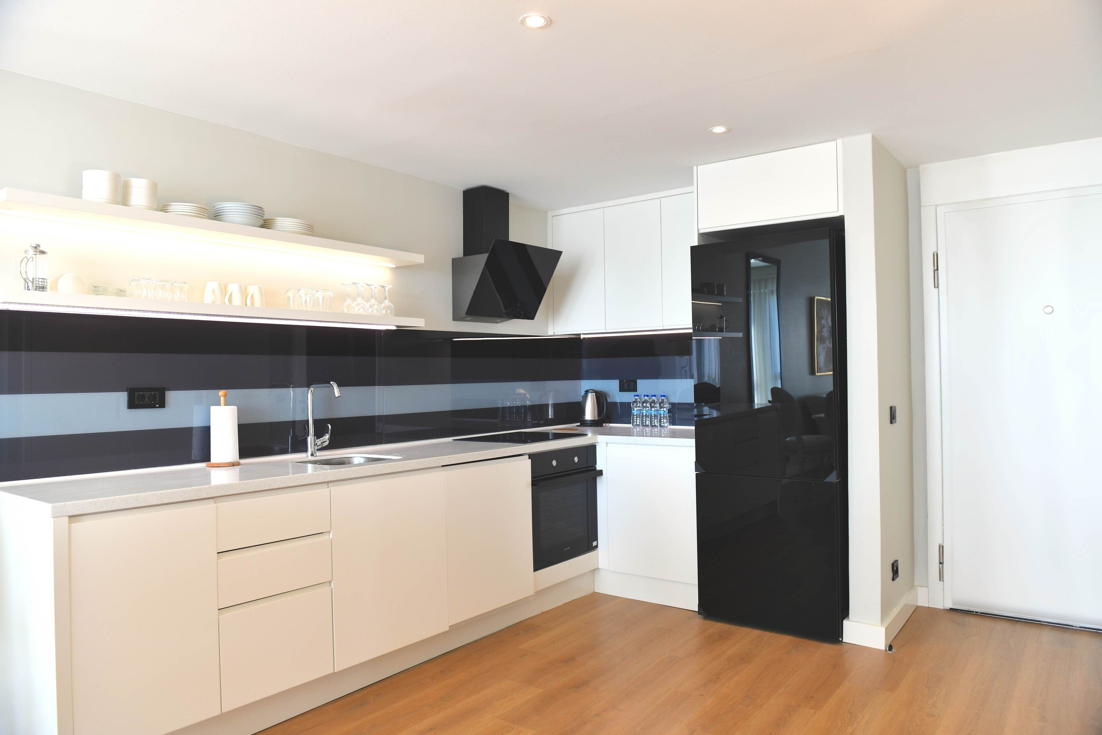 Una cocina moderna con armarios blancos, una estufa negra y piso de madera.
