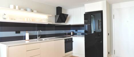 Una cocina moderna con armarios blancos, una estufa negra y piso de madera.