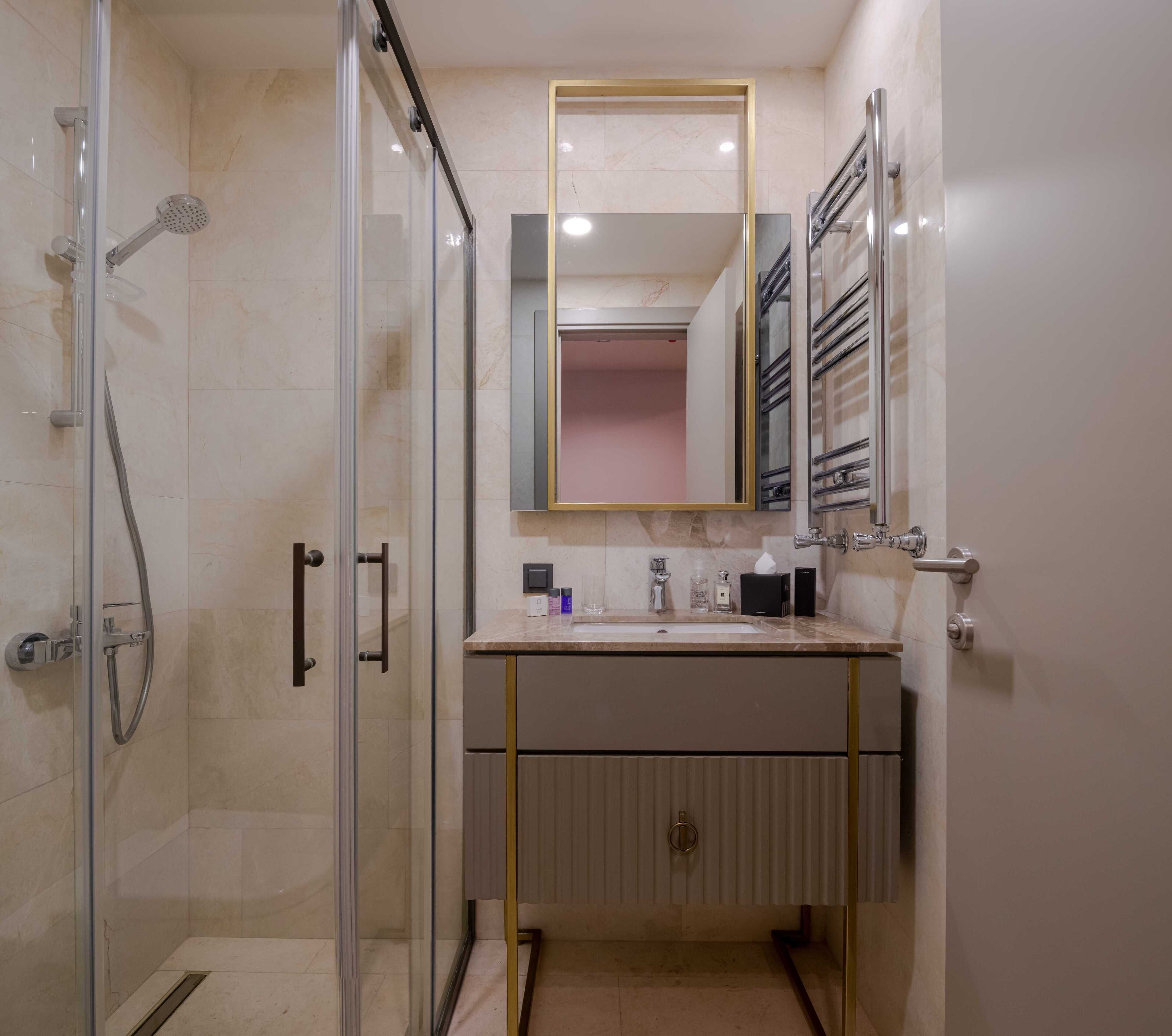 Un baño moderno con ducha de vidrio, tocador con espejo y barra para toallas.