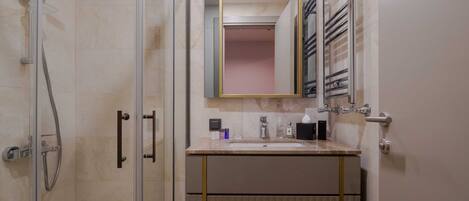 Un baño moderno con ducha de vidrio, tocador con espejo y barra para toallas.