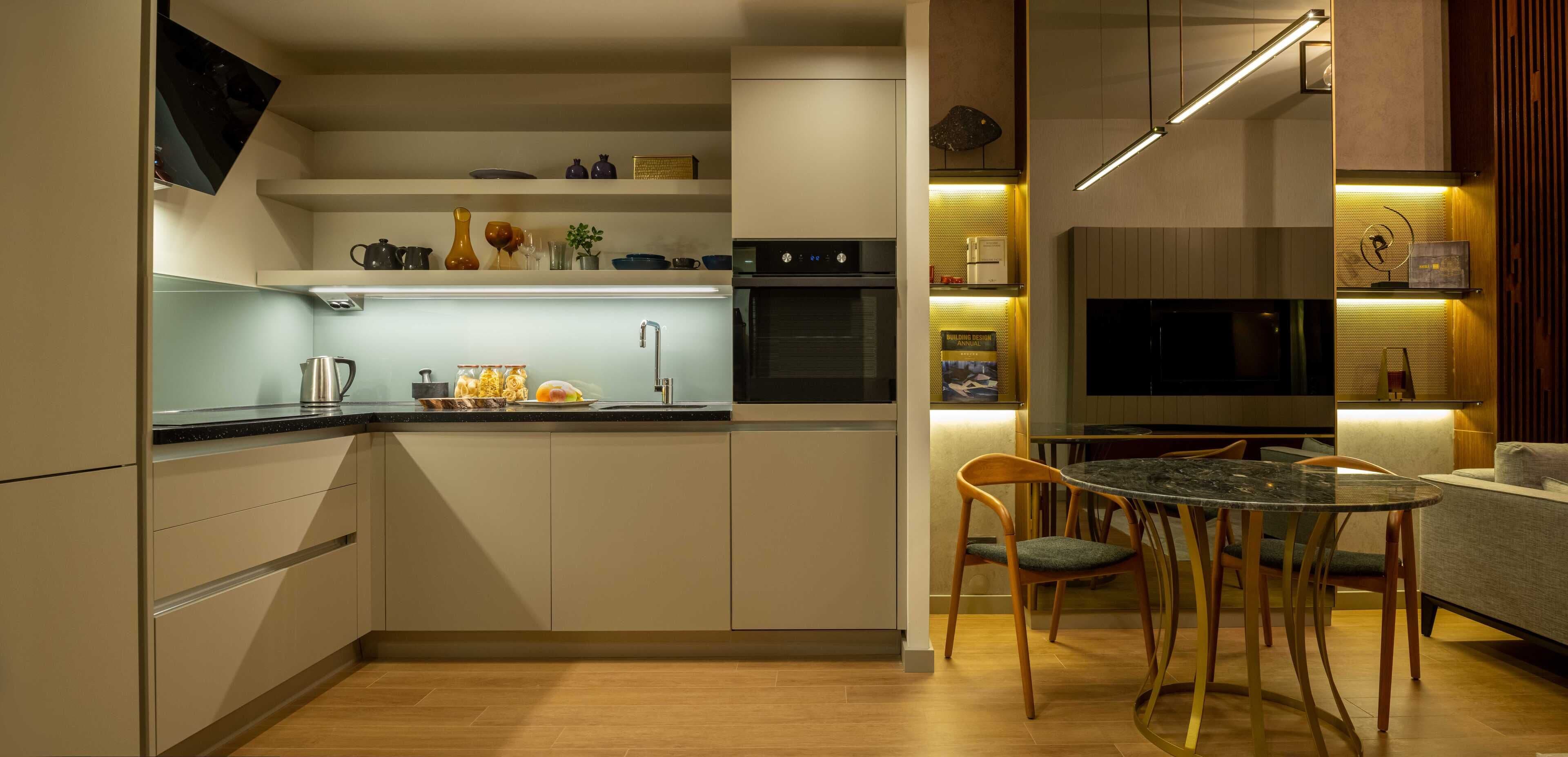 Une cuisine moderne dotée d’appareils électroménagers intégrés, un coin repas avec une table en verre et un téléviseur à écran plat.