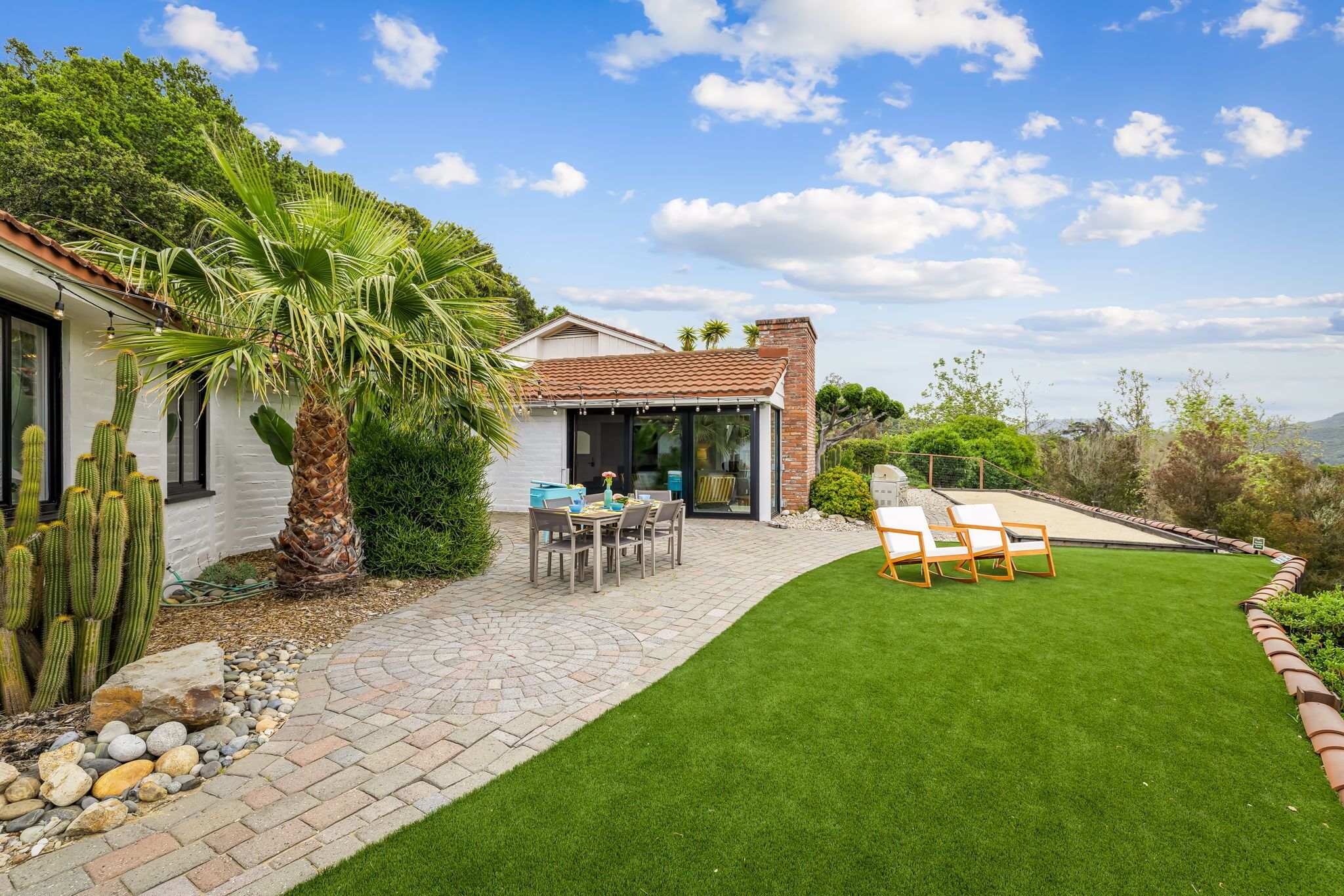 Une maison avec un patio, un coin repas et une pelouse.