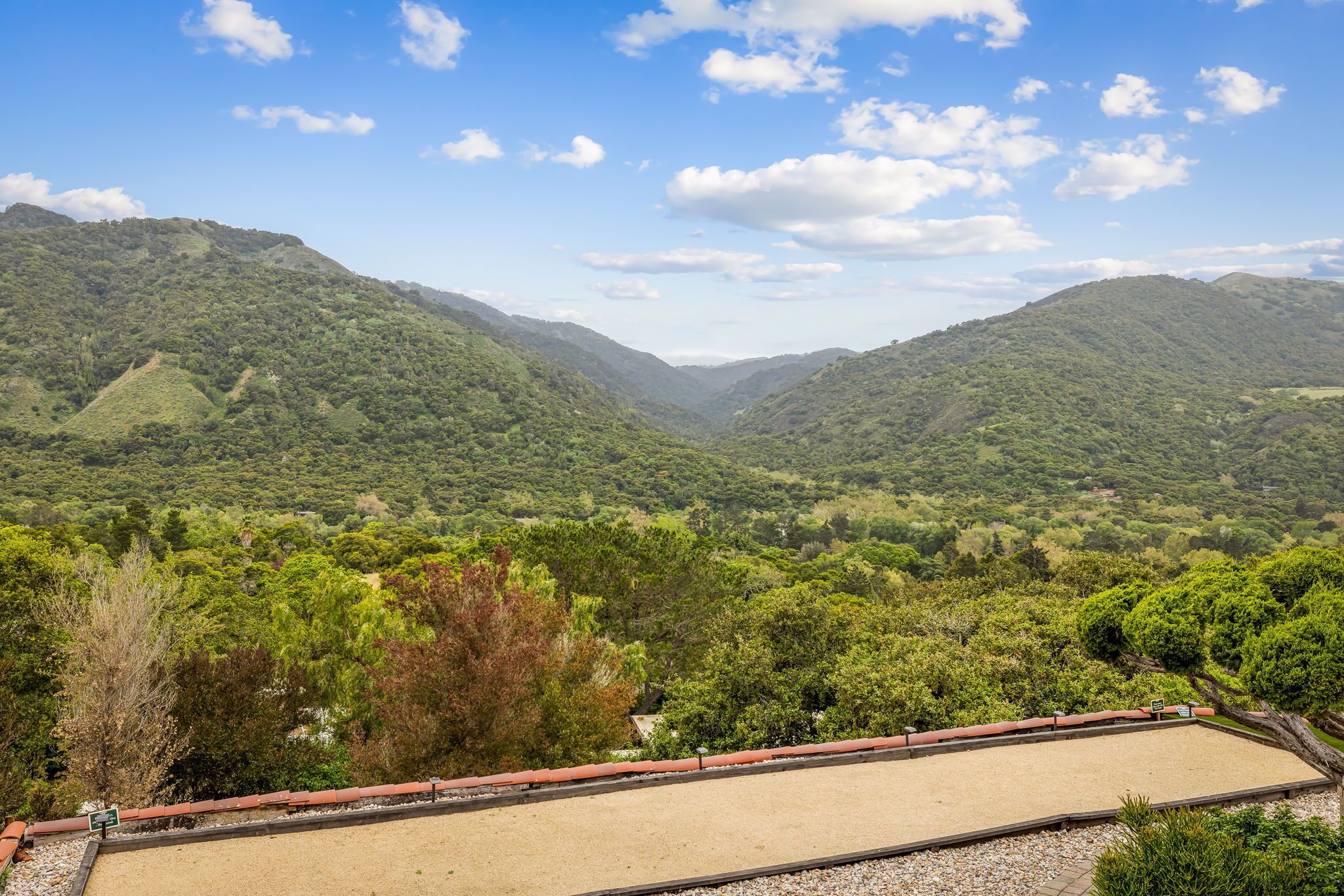 Une vue sur une vallée verdoyante, avec des montagnes en arrière-plan.