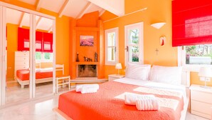 A bedroom with a large bed, a fireplace, a desk, and a window with a view of greenery. - Villa Anna Maria 3 Bedroom Private Pool (Heraklion)