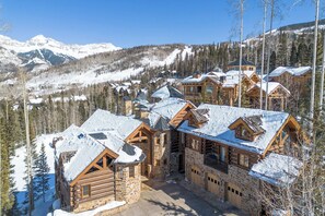 Un complexe hôtelier composé de plusieurs chalets en bois, entouré de montagnes et d’arbres couverts de neige.