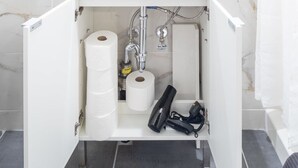 Un armari de bany amb paper higiènic, un assecador i un acumulador d'aigua.