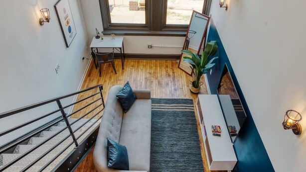 Un interior modern amb una escala, un sofà, una taula petita i una finestra gran que ofereix vistes al carrer.