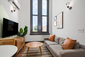 Uma sala de estar moderna com uma TV de tela plana, um sofá, uma mesa de centro e uma janela grande.