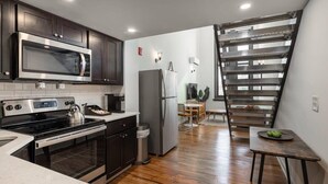 Une cuisine moderne avec des meubles de couleur sombre, des appareils électroménagers en acier inoxydable et un plancher en bois.