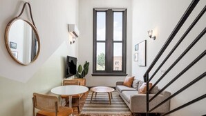 Un salon moderne comprenant un canapé, une table basse, un téléviseur et un coin repas avec des chaises et une table.