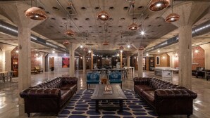 A spacious lobby with leather sofas, a central coffee table, and pendant lighting.