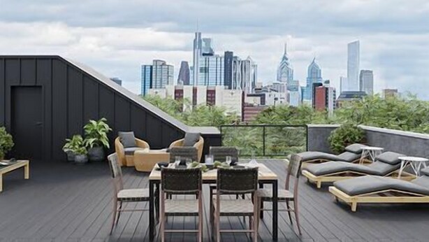 A rooftop terrace with a city skyline view, furnished with outdoor seating and tables.