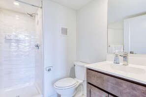 Een moderne badkamer met een douchecabine van glas, een wit toilet en een wastafel met spiegel.