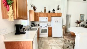 A kitchen with wooden cabinets, a white refrigerator, a stove, and a coffee maker.