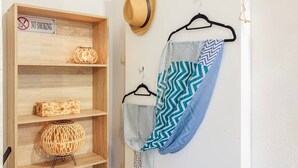 Een houten plank met een 'No Smoking' bord, een hoed en patroonstof aan kledinghangers.