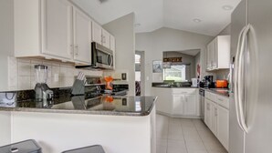 A modern kitchen with white cabinets, a central island, and a refrigerator.
