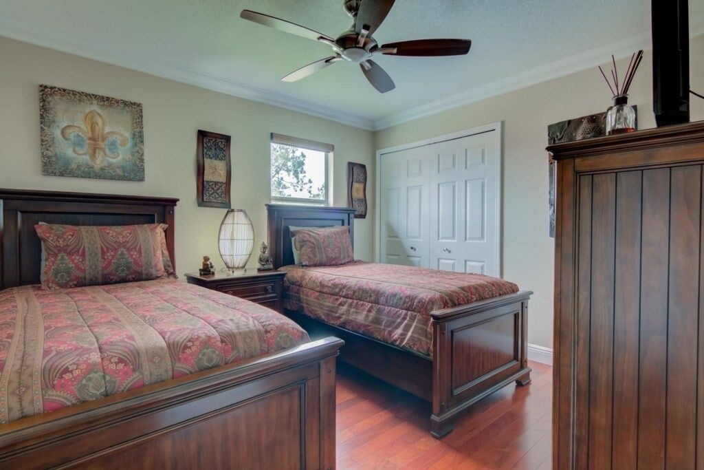 A bedroom with two beds, a ceiling fan, and a window.