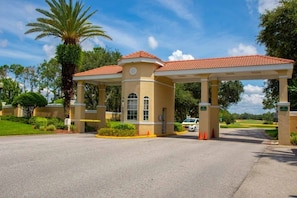 A covered entrance with a red-tiled roof, palm trees, and a parking area. - Golfer's Delight With Amazing Views Southern Dunes 4 Bedroom Home by RedAwning (Haines City)