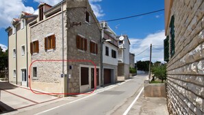 Vista de una calle con un edificio de piedra, cielo despejado y una carretera visible.
