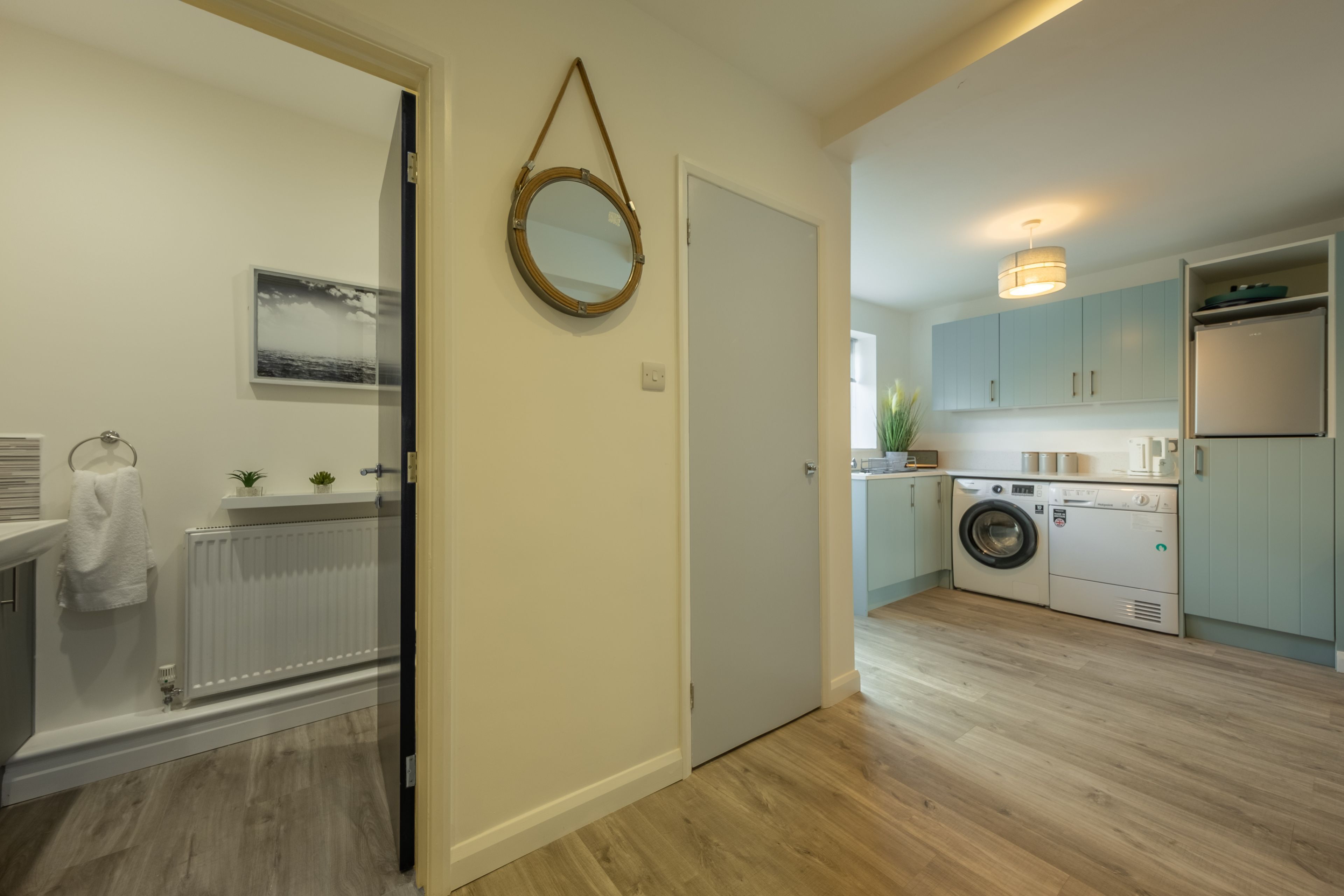 A modern kitchen with light blue cabinets, a built-in washing machine, and a refrigerator.
