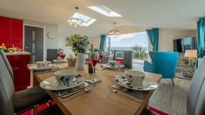 Un coin repas avec une table en bois dressée pour quatre personnes, un buffet rouge et une vue sur l’extérieur.