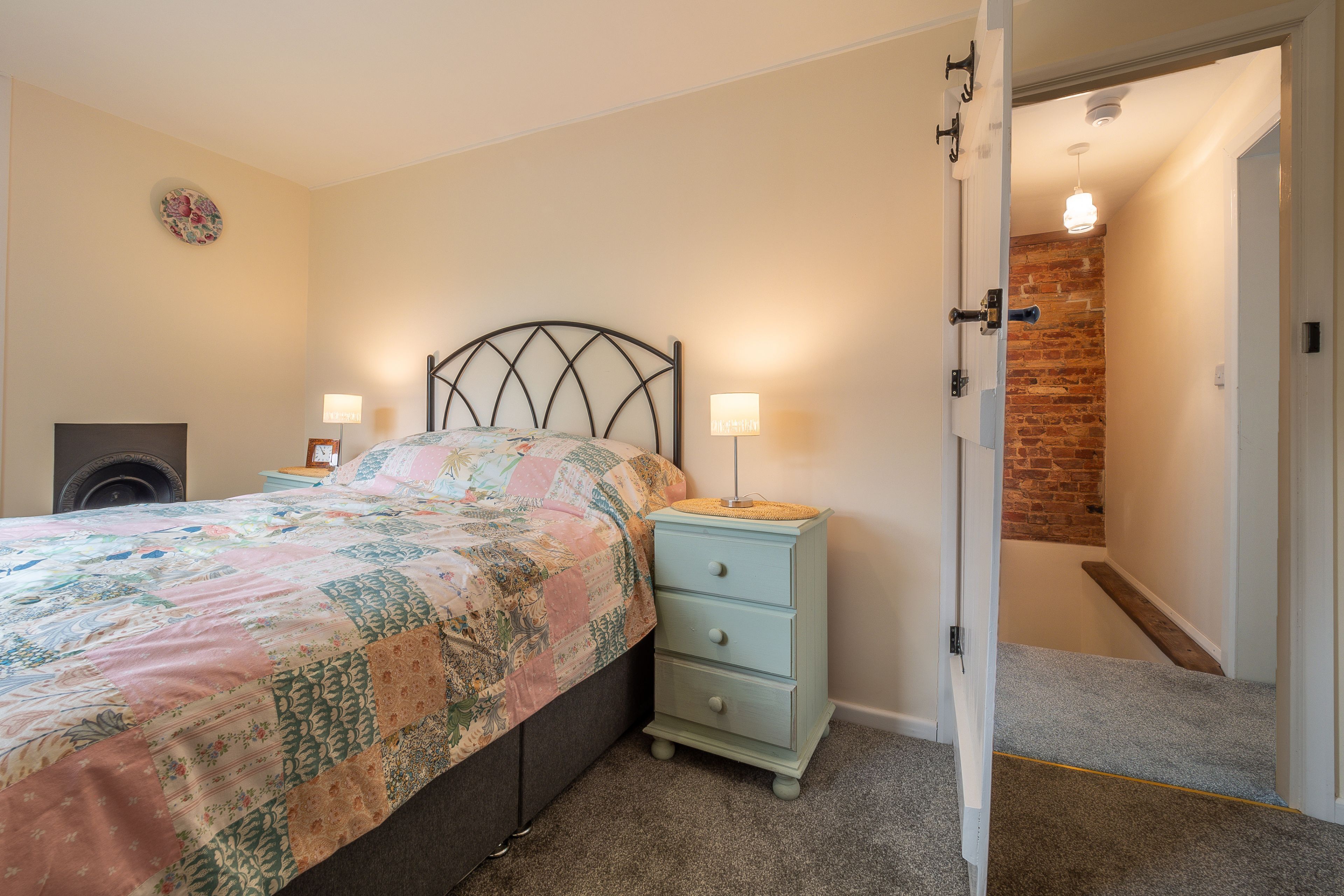 Un dormitorio con cama, mesitas de noche y una puerta que da a una escalera.