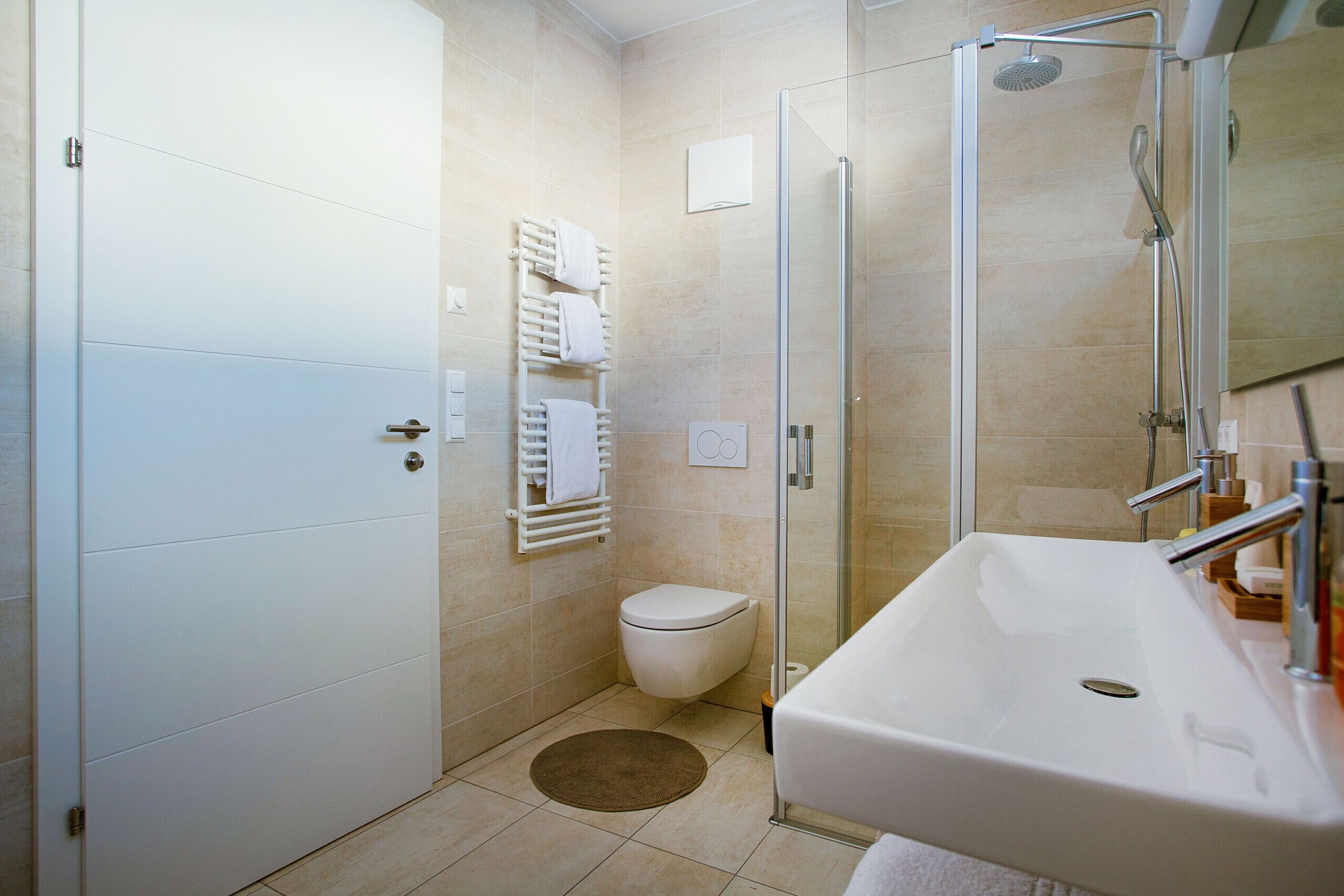 Un baño moderno con cabina de ducha de vidrio, un lavamanos blanco y un inodoro.
