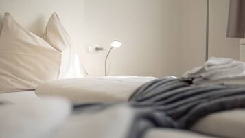 Ein ordentlich bezogenes Bett mit Kissen und einer Nachttischlampe.