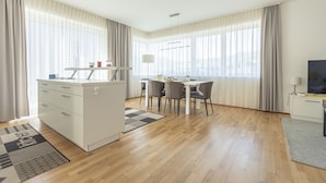 A modern hotel room with a kitchenette, dining area, and a large window with curtains. - Chalet # 19 for up to 8 people with IR- Sauna (St. Lambrecht)