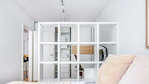 Une chambre moderne avec un grand lit, un dressing et une salle de bain visible à travers une porte ouverte.