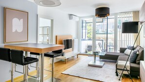 Un salon moderne avec un coin repas, de grandes fenêtres et un balcon.