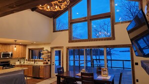 A spacious kitchen with wooden cabinets, a dining area with a table and chairs, and large windows offering a view of a snowy landscape.