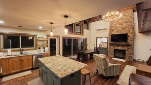 A modern kitchen with a large island, wooden cabinets, and a stone accent wall.