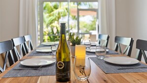 Una mesa de comedor dispuesta con platos, una botella de vino, una vela y una copa.