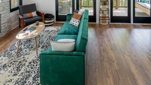 Un salón amplio con un sofá verde, un espejo redondo y techo de madera.