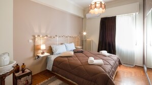 Un lit bien fait, recouvert d’une couverture marron, une lampe de chevet et une table de chevet avec une autre lampe.