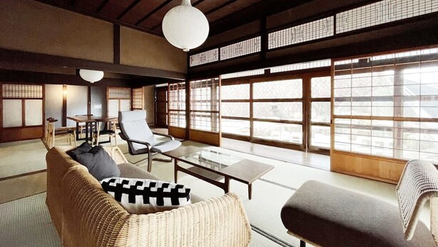 A traditional Japanese-style room with tatami flooring, a low table, and a sofa with cushions.