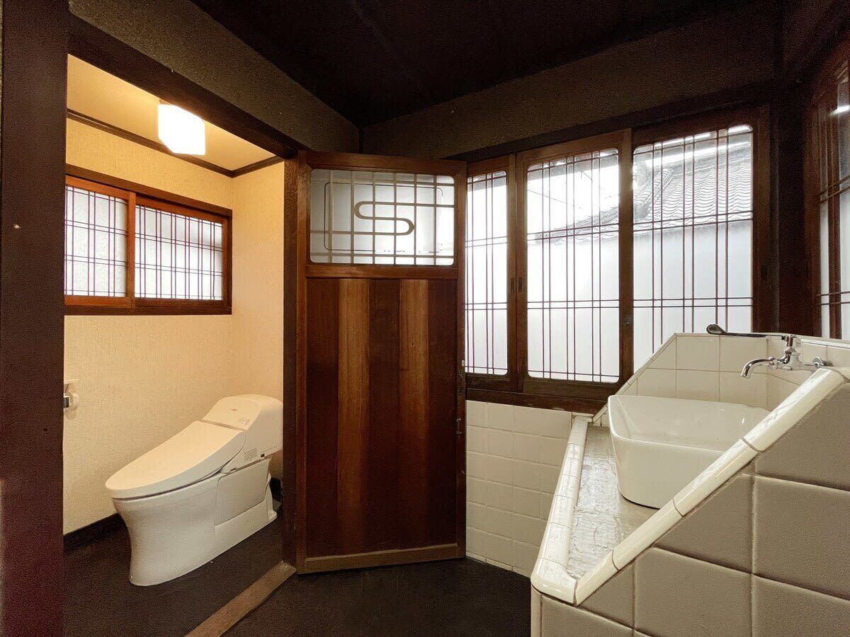 A small, compact bathroom with a toilet, a bathtub, and a window with frosted glass.