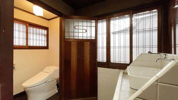 A small, compact bathroom with a toilet, a bathtub, and a window with frosted glass.