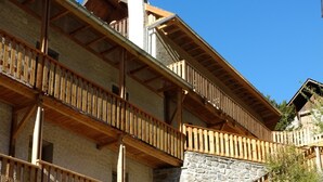Een meerhoog gebouw met houten balkons en stenen trappen.