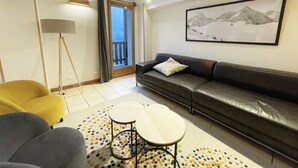 Een moderne woonkamer met een bank, een gele fauteuil, een grijze fauteuil, een vloerlamp en een kamerkleed met een patroon.