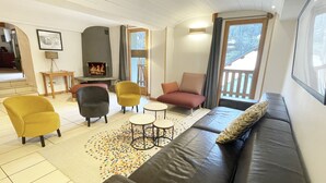 Een gezellige woonkamer met een open haard, een bank, fauteuils en een salontafel.