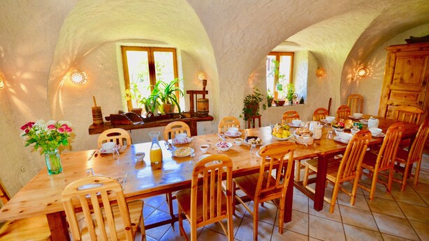 A dining area with a long wooden table set for a meal, surrounded by wooden chairs. - Magnificent detached chalet★7 bedrooms★prox. Alpe d'Huez (LE BOURG D'OISANS)