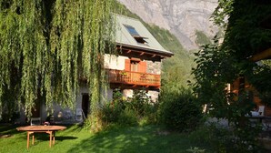A rustic chalet with a wooden balcony, surrounded by lush greenery and a mountain backdrop. - Magnificent detached chalet★7 bedrooms★prox. Alpe d'Huez (LE BOURG D'OISANS)
