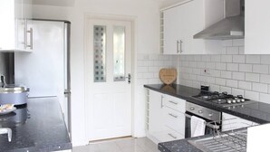 Uma cozinha moderna com armários brancos, bancada preta e exaustor de aço inoxidável.