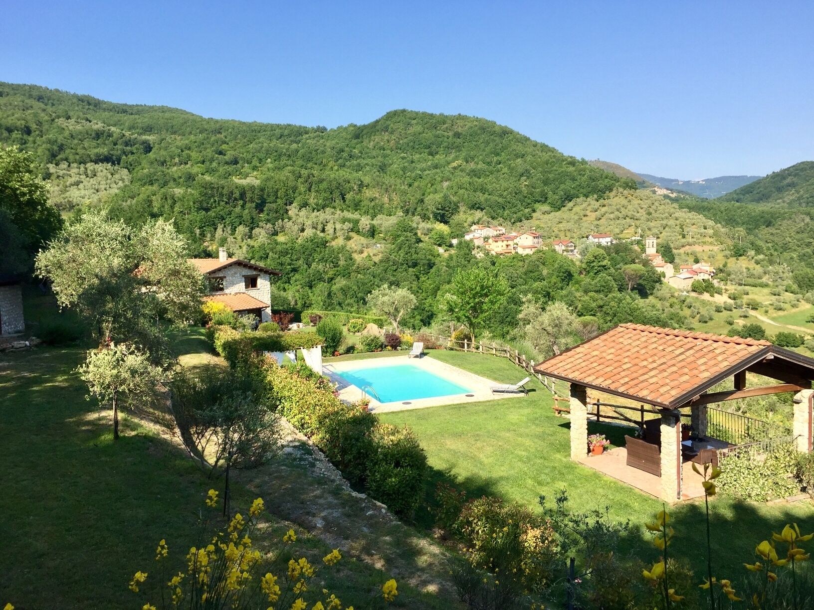 A villa with a swimming pool, surrounded by lush greenery and hills.
