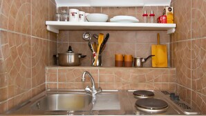 A kitchen with a stainless steel sink, a stove, and a shelf above the sink holding kitchen utensils and dishes. - A3 - Best Location in Center With the sea View (Vodice)