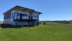 Une maison moderne à deux étages, dotée d’un balcon, de grandes fenêtres et d’une pelouse bien entretenue.