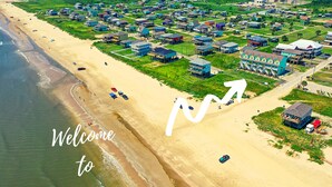 Vista aérea de uma área costeira com casas de praia e uma grande seta apontando para a direita.